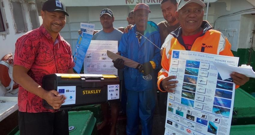 Fishermen hold toolkits and awareness materials 