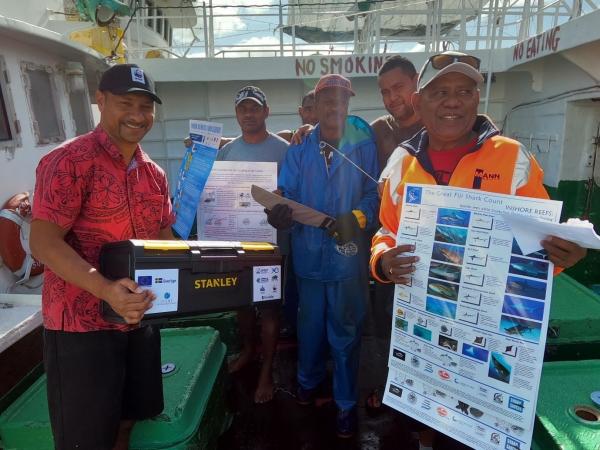 Fishermen hold toolkits and awareness materials 